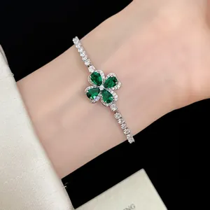 Close-up of elegant four-leaf clover bracelet with emerald green stones for women.