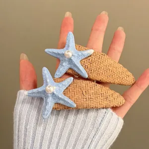 Detailed close-up of blue starfish hair clips with pearl accents on straw woven base.