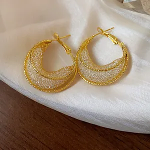 Macro detail of golden mesh hoop earrings showcasing the intricate glass weave design