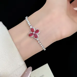 Elegant silver clover bracelet featuring brilliant red stones and white zircons on wrist.