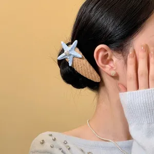 Close-up shot of a blue starfish pearl hair clip worn on a model's black hair.