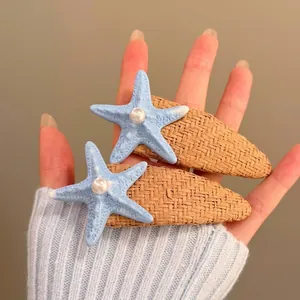 Close-up detail of blue starfish pearl hair clips featuring woven straw base design