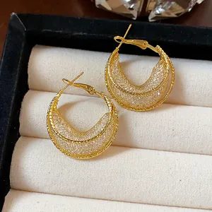 Detailed view of elegant gold mesh hoop earrings resting in a cream jewelry display box