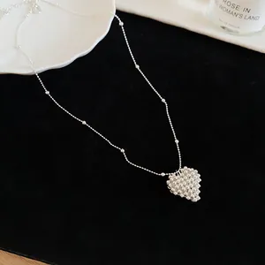 Detailed view of a silver-toned beaded heart pendant necklace resting on black velvet