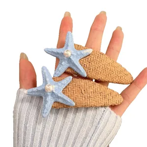 Pair of blue starfish hair clips with pearls and straw weave base for beach vacations.