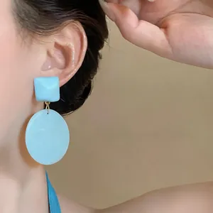 Primo piano dettagliato di orecchini pendenti geometrici in resina blu chiaro su modella