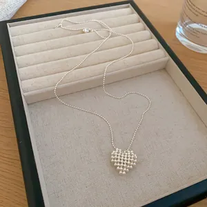 Detail view of a minimalist silver beaded heart pendant necklace on a jewelry tray.