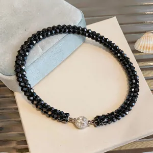 Gros plan d'un collier tressé en perles de verre noires avec fermoir en cristal