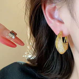 Close-up detail of golden mesh texture hoop earring worn by model for elegant style