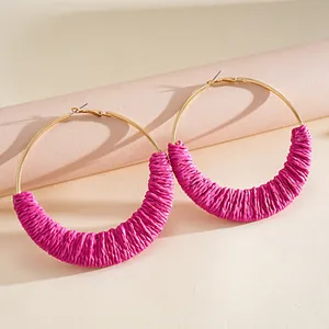Λεπτομερής λήψη από χειροποίητα ροζ πλεκτά σκουλαρίκια κρίκους σε ουδέτερο φόντο