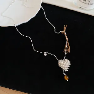 Detailed macro shot of a beaded silver heart pendant necklace with a tiger eye charm