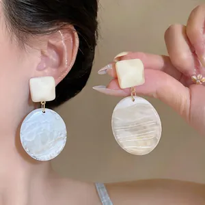 Eleganti orecchini pendenti geometrici in resina crema per un look estivo chic.