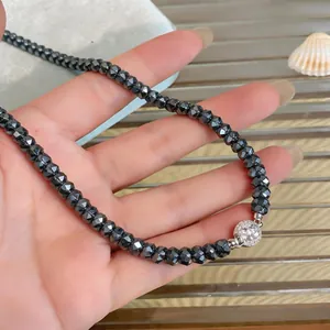 Gros plan d'un élégant collier en perles de verre noires facettées avec fermoir pavé brillant