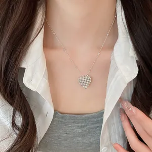 Close-up of a minimalist silver beaded heart pendant necklace on a woman's neck