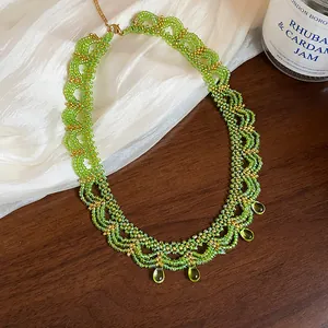 Gros plan d'un collier en dentelle de perles de verre vertes avec accents dorés et gouttes