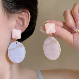 Vista dettagliata di orecchini geometrici in resina rosa con motivo marmorizzato