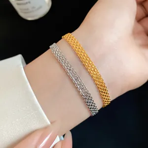 Close-up view of gold and silver mesh chain bracelets worn on a wrist with elegant styling.