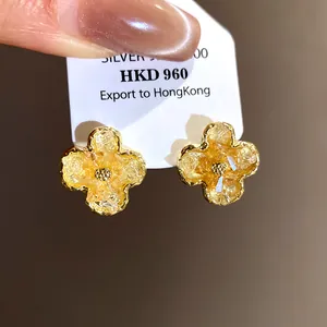 Close-up of gold-tone floral earrings with gradient yellow crystal inlay