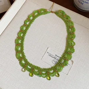 Détail du collier en perles de verre vertes avec des accents dorés et des pendentifs en goutte.