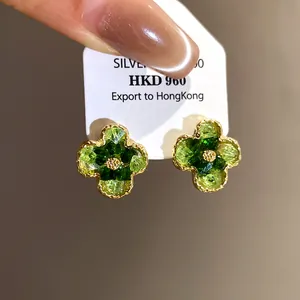 Close-up detail of vintage style green gradient flower earrings with gold-toned borders