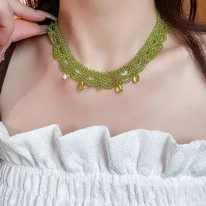 Gros plan d'un tour de cou en perles de verre vertes avec des pendentifs en forme de goutte.