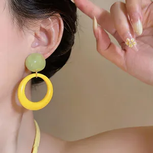 Close-up of vibrant dopamine style resin drop earrings with green and yellow contrast.
