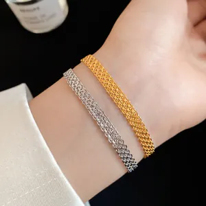 Detailed close-up showing texture of gold and silver woven chain bracelets on a wrist
