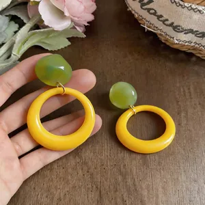 Detailed view of dopamine style resin earrings featuring green beads and yellow rings