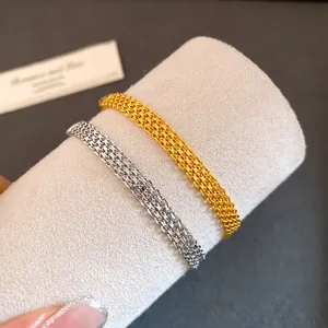 Close-up of gold and silver mesh chain bracelets with high-end woven texture detail.
