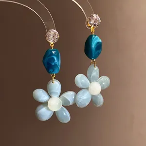Close-up of zircon resin flower drop earrings in blue vacation style