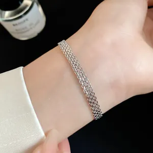 Detailed macro view of a silver multi-layered chain bracelet worn on a female wrist
