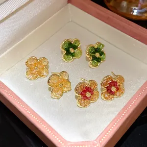 Close-up of gradient flower stud earrings featuring delicate crushed stone texture and gold trim