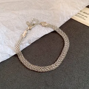 Close-up of a silver multi-layered mesh chain bracelet on a textured background