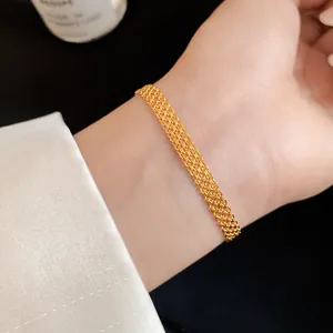 Elegant close-up detail of a minimalist gold multi-layered mesh chain bracelet worn on wrist