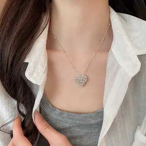 Detail shot of a minimalist silver-toned beaded heart pendant necklace worn by a model