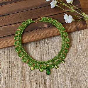 Collier de perles vertes fait main avec accents dorés et élégants pendentifs en forme de goutte.