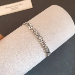 Detailed close-up of a layered silver mesh chain bracelet on a soft display stand