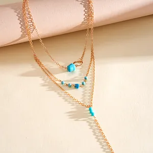 Close-up of vintage multi-layered gold chain necklace with turquoise stone beads
