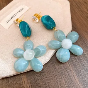 Macro detail of resin flower drop earrings with marbled petals and zircon accents.