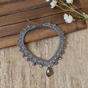 Collier ras-du-cou en perles grises avec cristaux en forme de goutte d'eau.