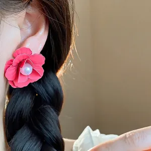 Exquisite red spray-painted flower pearl stud earrings for women shown worn on ear