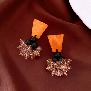 Close-up of vintage ethnic style brown wood and glass bead tassel stud earrings on fabric