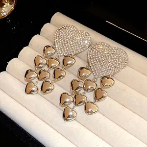 Elegant silver heart tassel earrings with sparkling rhinestones on jewelry display.