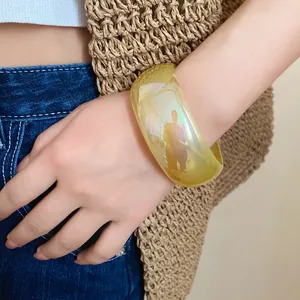 Gros plan d'un large bracelet en résine jaune transparente avec une finition irisée