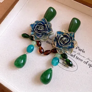Vintage blue resin rose earrings with emerald crystal drop pendants in a jewelry box