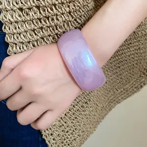 Gros plan d'un large bracelet en résine transparente violette porté au poignet