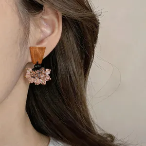 Detailed view of retro ethnic earrings with brown wood and pink glass beads worn on ear