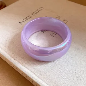 Gros plan d'un large bracelet en résine transparente lavande sur un livre minimaliste