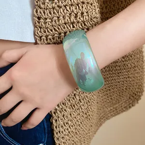 Vue détaillée d'un large bracelet en résine avec fini gelée irisé sur le poignet