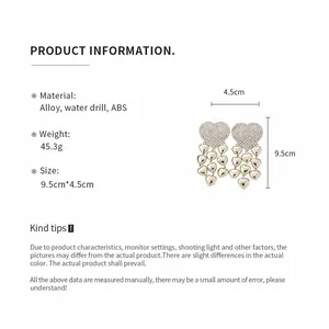 Detail view of oversized heart tassel earrings with dimensions and material specs